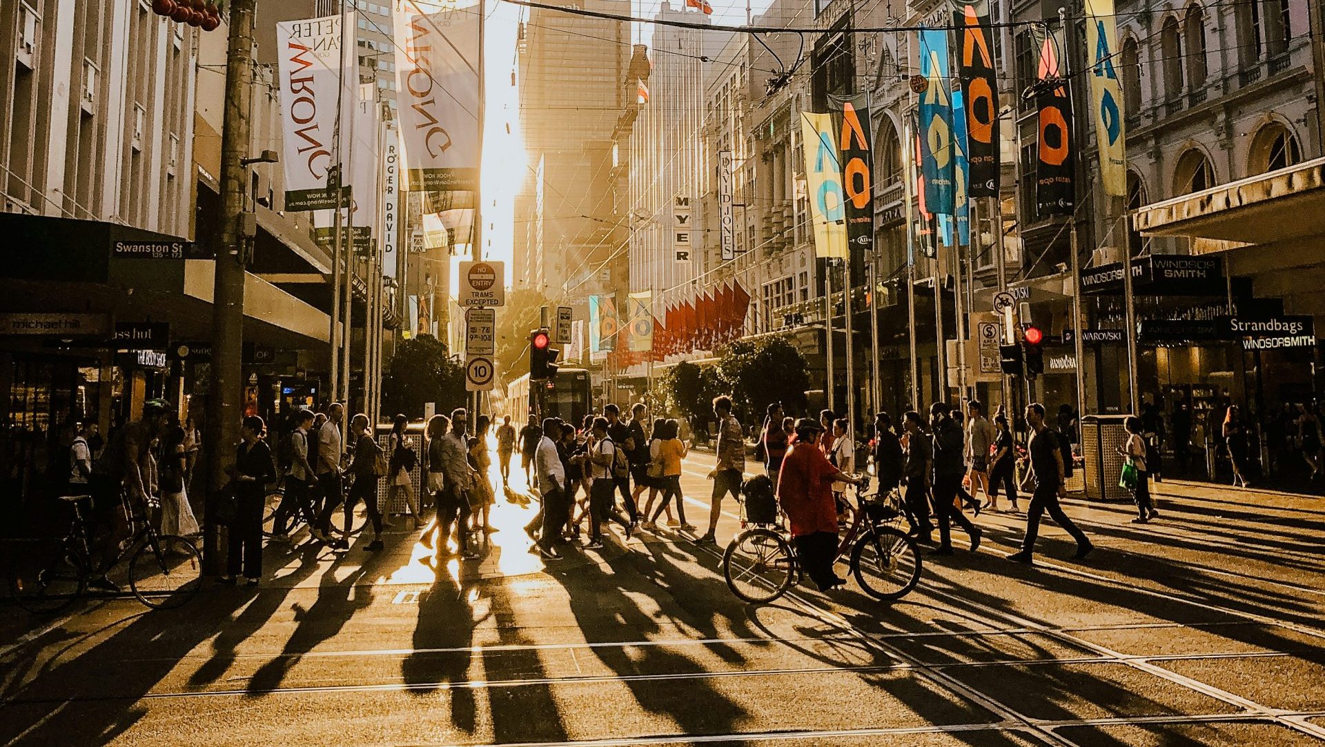 People walking on city street during sunset
